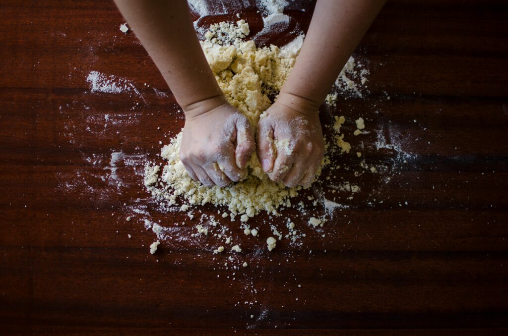 Two hands kneading bread dough on table
